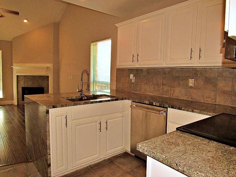 313 Timbercreek Court, Princeton, TX 75407 Kitchen featuring white shaker-style cabinetry, stone countertops with waterfall edge, stainless steel dishwasher, square tile backsplash, and a high-arch kitchen faucet