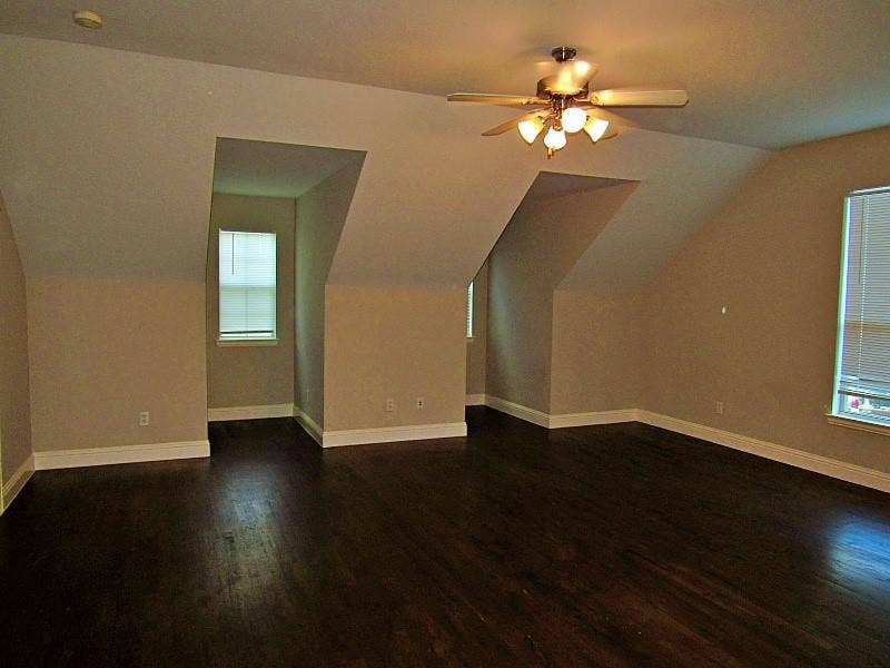 313 Timbercreek Court, Princeton, TX 75407 Open-concept room featuring vaulted ceilings, dark wood-finish flooring, two deep dormer alcoves, and a central ceiling fan with multi-light fixture