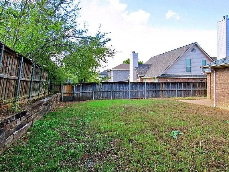 313 Timbercreek Court, Princeton, TX 75407 Rear yard featuring timber retaining walls, wood fencing, and a concrete patio