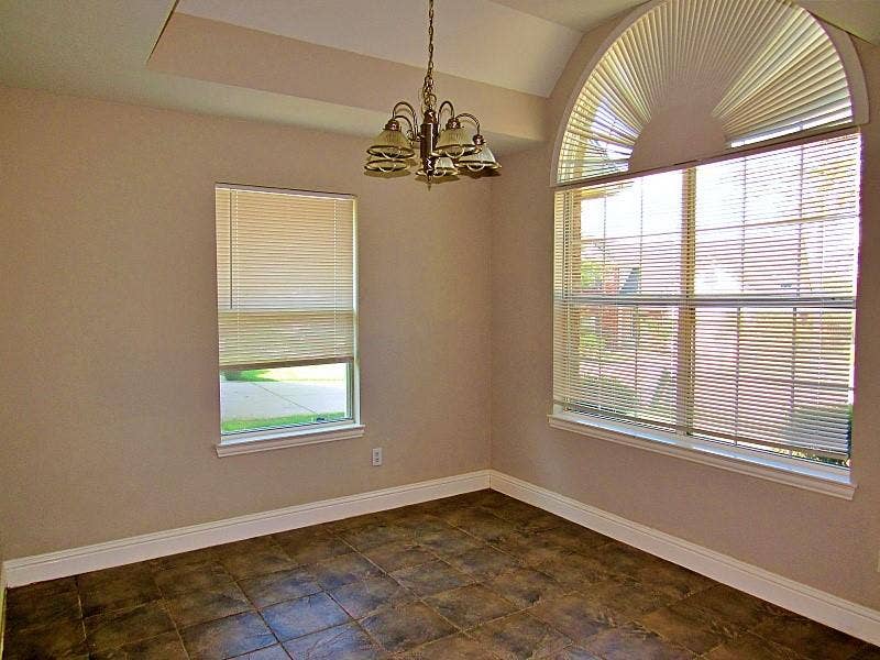 313 Timbercreek Court, Princeton, TX 75407 Tray ceiling with a multi-arm chandelier, large arched window, and ceramic tile flooring