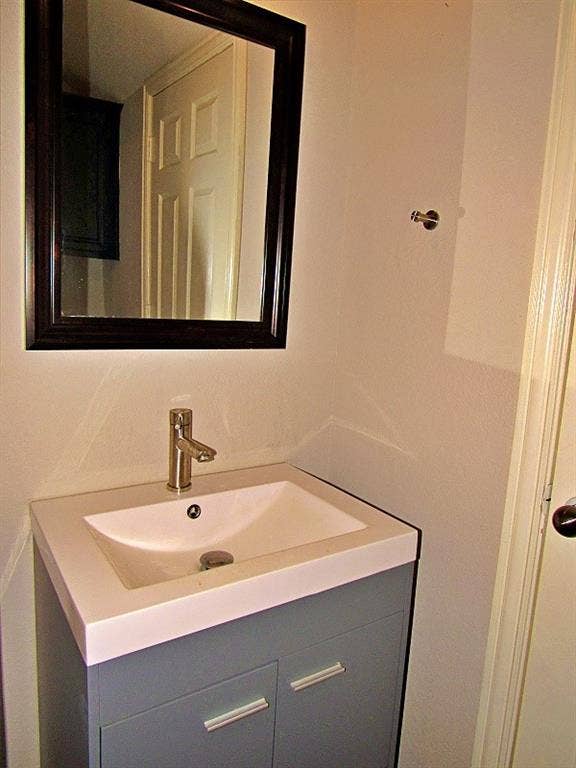 313 Timbercreek Court, Princeton, TX 75407 Grey vanity featuring a rectangular integrated sink, brushed metal single-handle faucet, and dark-finish framed wall mirror