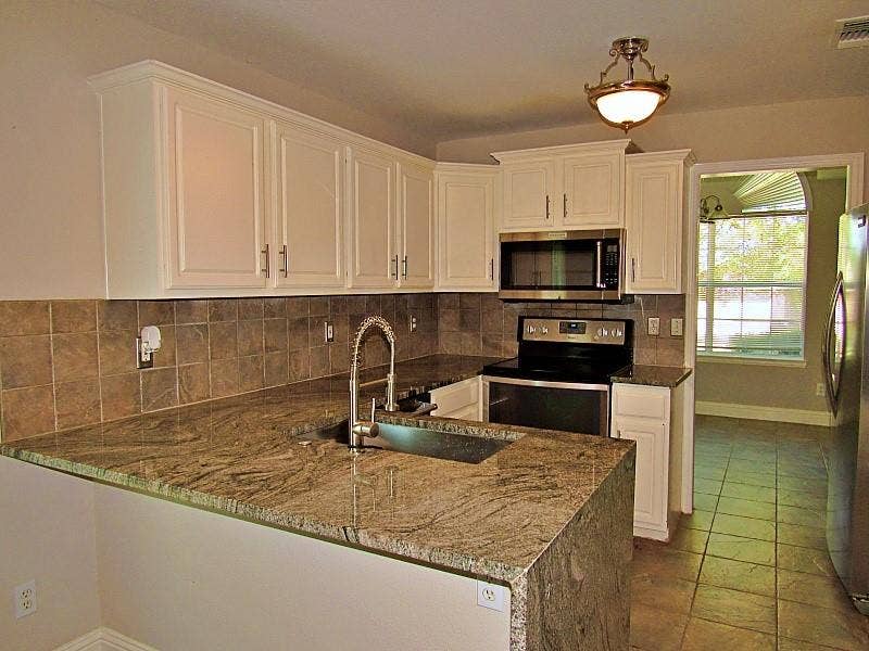 313 Timbercreek Court, Princeton, TX 75407 Kitchen featuring white cabinetry, stone countertops, square tile backsplash, stainless steel appliances, and a high-arch faucet