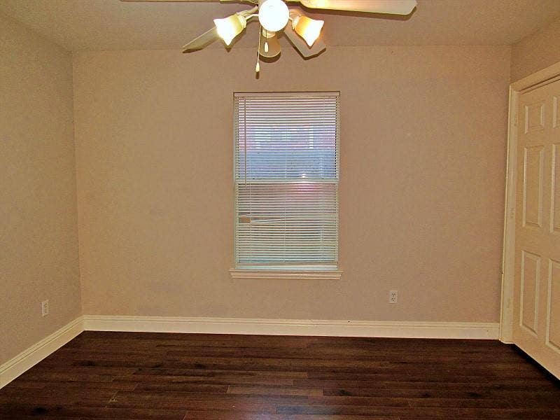 313 Timbercreek Court, Princeton, TX 75407 Interior room featuring dark wood-finish flooring, neutral wall paint, a central ceiling fan with multi-directional lighting, a single window with slatted blinds, and a six-panel interior door