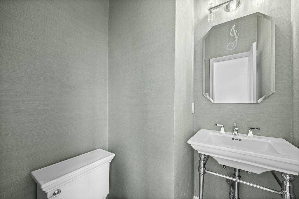 Textured wall coverings, chrome-finished console sink with integrated basin, polished chrome widespread faucet, and beveled-edge wall mirror