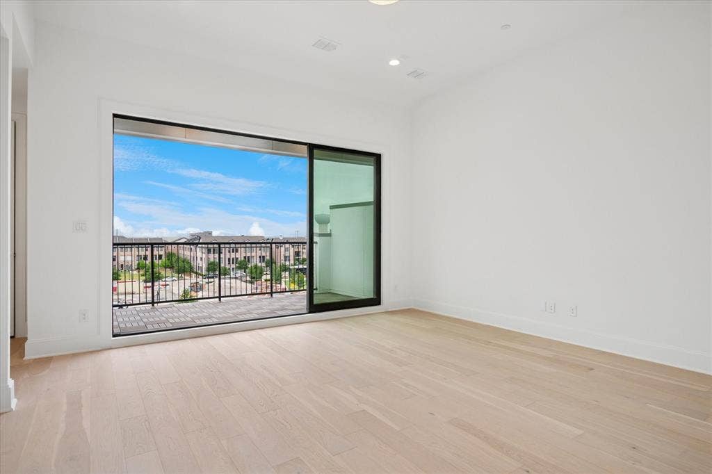 Spacious room featuring light wood-finish flooring, white walls, and a large sliding glass door