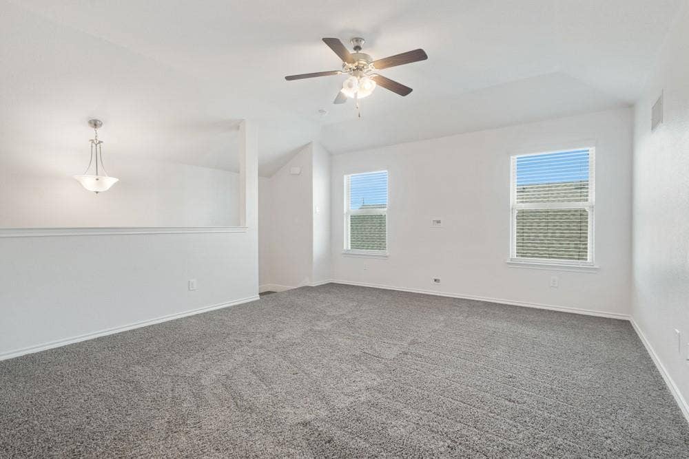Vaulted ceilings, neutral carpeting, a central ceiling fan with integrated lighting, and dual windows