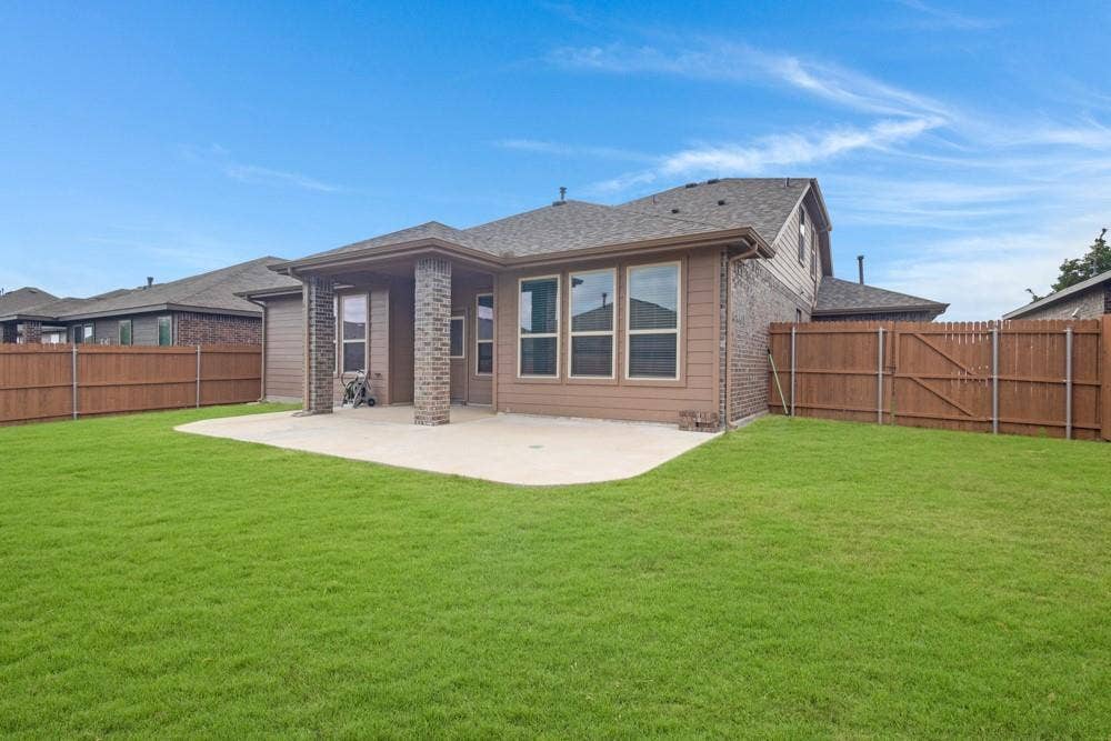 Rear exterior featuring a covered patio with masonry columns, lap siding, a concrete patio slab, and a wood privacy fence enclosing the lawn