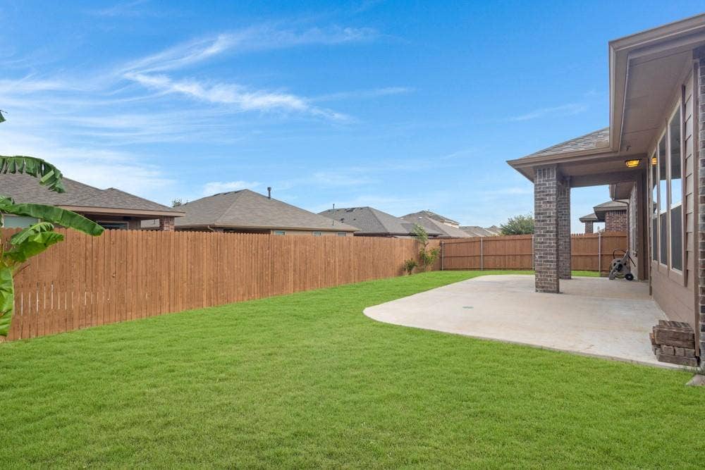 Backyard featuring a concrete patio, covered porch with brick pillars, and perimeter wood privacy fencing