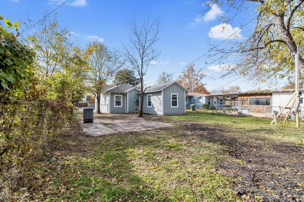 3023 Spurlock Street, Dallas, TX 75223 Exterior siding, concrete patio, and mature trees on a lot with established perimeter fencing