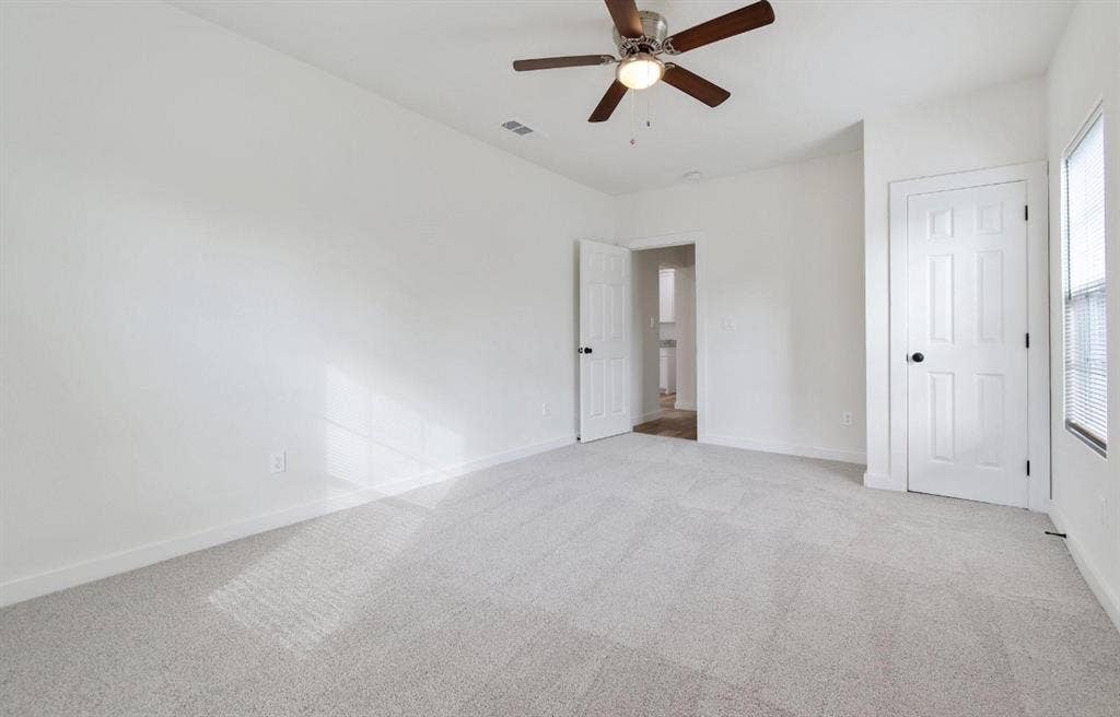 3023 Spurlock Street, Dallas, TX 75223 Neutral-toned wall-to-wall carpeting, multi-panel interior doors, and a ceiling-mounted fan with integrated lighting