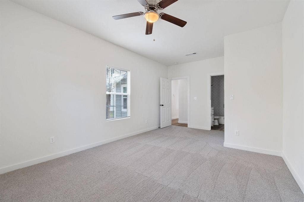 3023 Spurlock Street, Dallas, TX 75223 Neutral-toned wall-to-wall carpeting, central ceiling fan with integrated lighting, single-pane window, and interior door leading to a tiled-finish bathroom