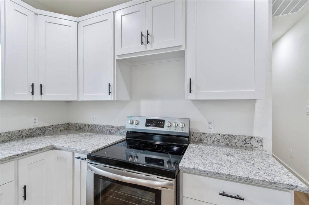 3023 Spurlock Street, Dallas, TX 75223 White shaker-style cabinetry with matte black hardware, stone-patterned countertops, and a stainless steel freestanding range