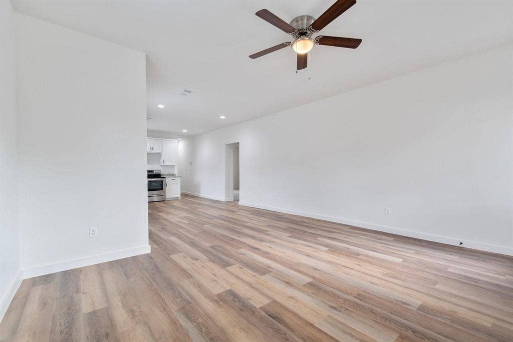 3023 Spurlock Street, Dallas, TX 75223 Neutral-toned wall finish, wood-finish flooring, recessed lighting, and a multi-blade ceiling fan with an integrated light fixture