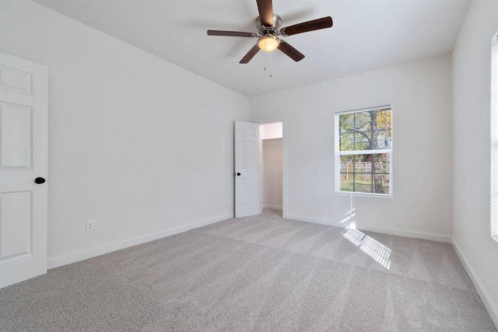 3023 Spurlock Street, Dallas, TX 75223 Neutral-toned carpeting, ceiling fan with integrated light fixture, multi-pane window, and interior paneled doors