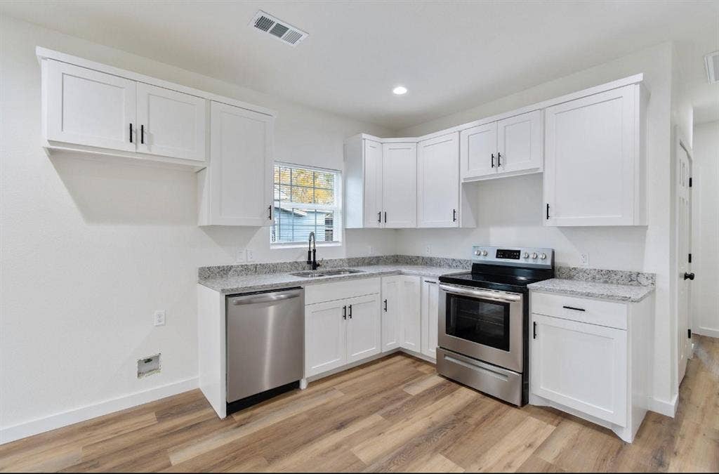 3023 Spurlock Street, Dallas, TX 75223 Kitchen featuring white shaker-style cabinetry, stone-finish countertops, stainless steel appliances, a high-arc faucet, and wood-finish flooring