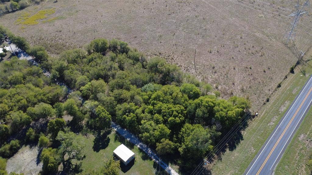 147 Private Road 4330, Greenville, TX 75401 Expansive lot featuring mature hardwood trees, open grassland, and a single-story outbuilding with a metal roof