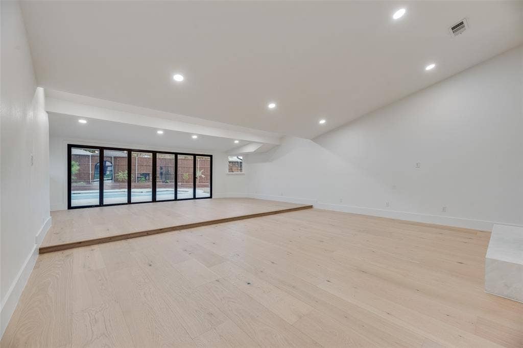 Sunken living area featuring wood-finish flooring, vaulted ceilings, recessed lighting, and multi-panel folding glass doors