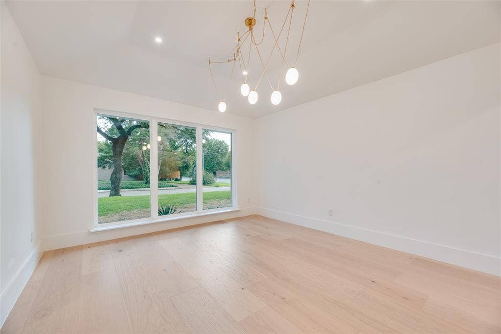 Light-filled room featuring wood-finish flooring, a contemporary multi-arm pendant chandelier, a vaulted ceiling, and oversized picture windows