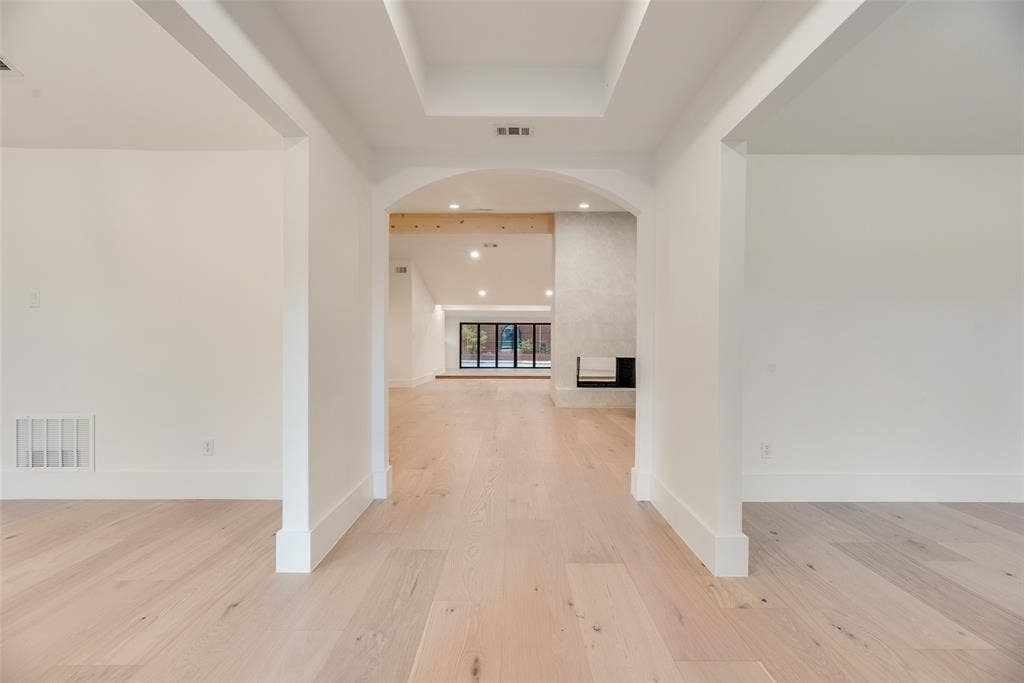 Tray ceiling, arched entryway, wood-finish flooring, recessed lighting, and built-in fireplace