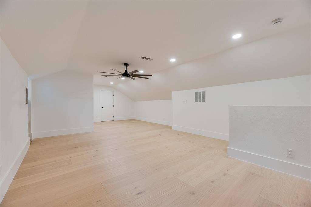 Open-concept area featuring wood-finish flooring, vaulted ceilings, recessed lighting, and a multi-blade ceiling fan