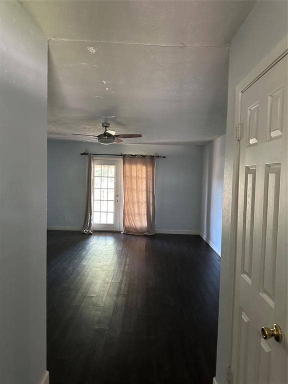 Interior space featuring dark wood-finish flooring, a ceiling fan with integrated lighting, and a glass-paneled exterior door