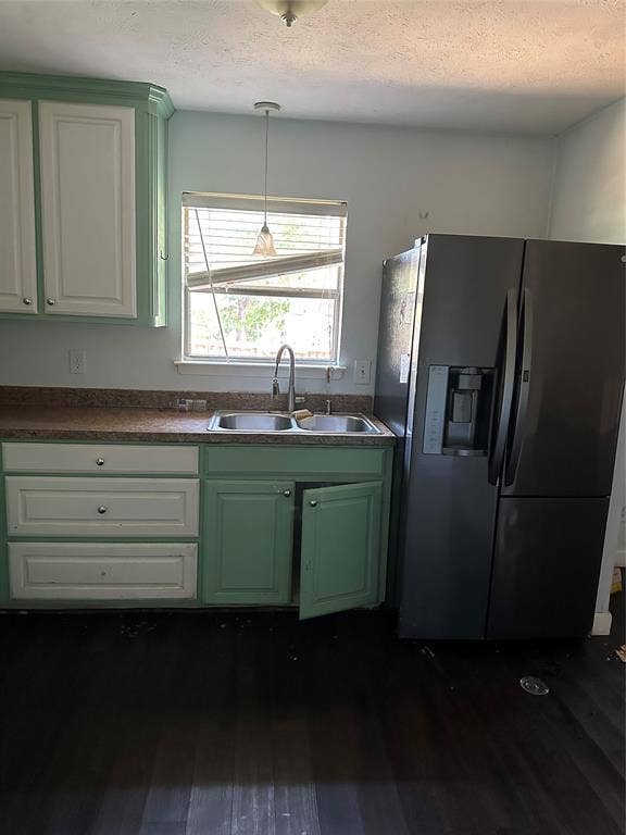 Kitchen area featuring two-tone cabinetry, stone-finish countertops, dual-basin stainless steel sink, polished chrome faucet, and wood-finish flooring