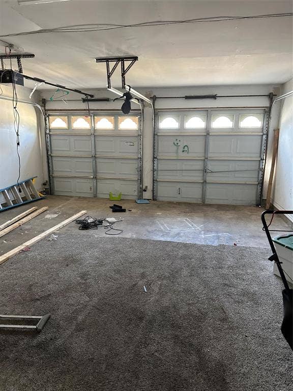 Two-car garage featuring segmented overhead doors with arched-top window panels and two motorized automatic openers