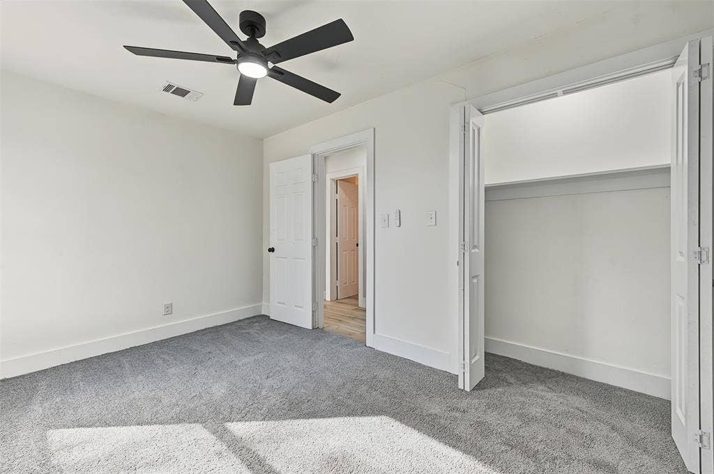 Interior space featuring wall-to-wall carpeting, matte black multi-blade ceiling fan with integrated lighting, and white six-panel interior doors