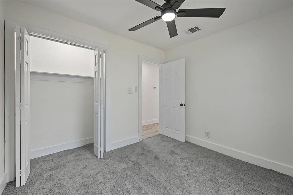 Interior space featuring wall-to-wall carpeting, a multi-blade ceiling fan with integrated lighting, a dual-paneled closet door, and a solid-core interior door