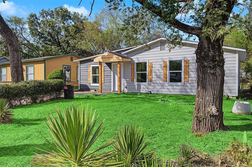 Exterior featuring horizontal siding, decorative wood shutters, a covered front entryway, and established mature trees