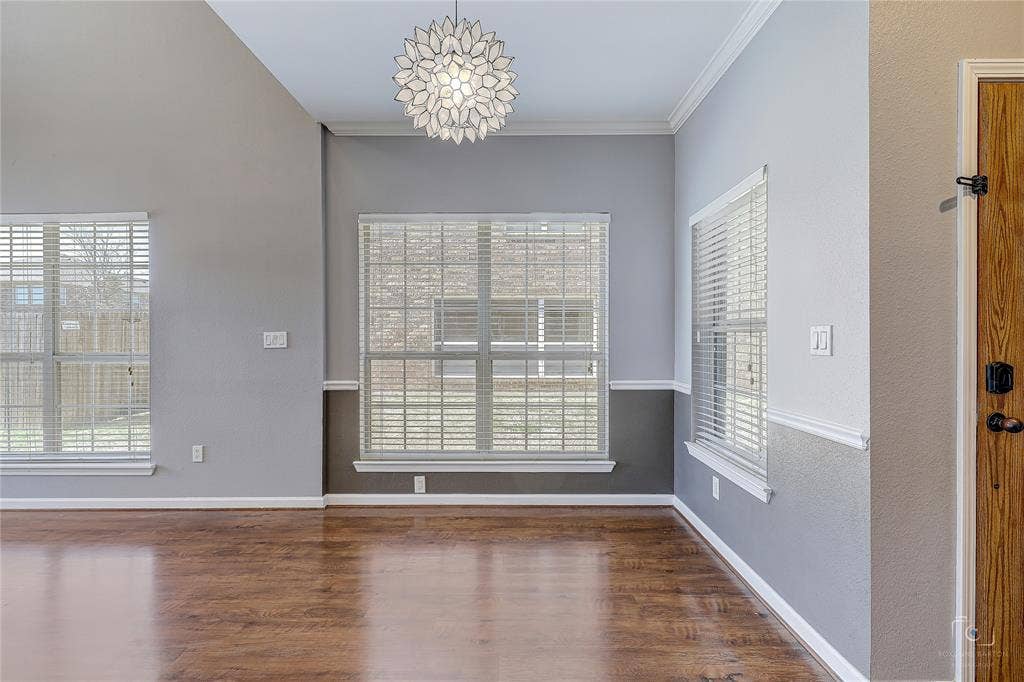 Vaulted ceilings, wood-finish flooring, two-tone wall treatment with chair rail molding, multi-pane windows, and a decorative petal-style pendant fixture