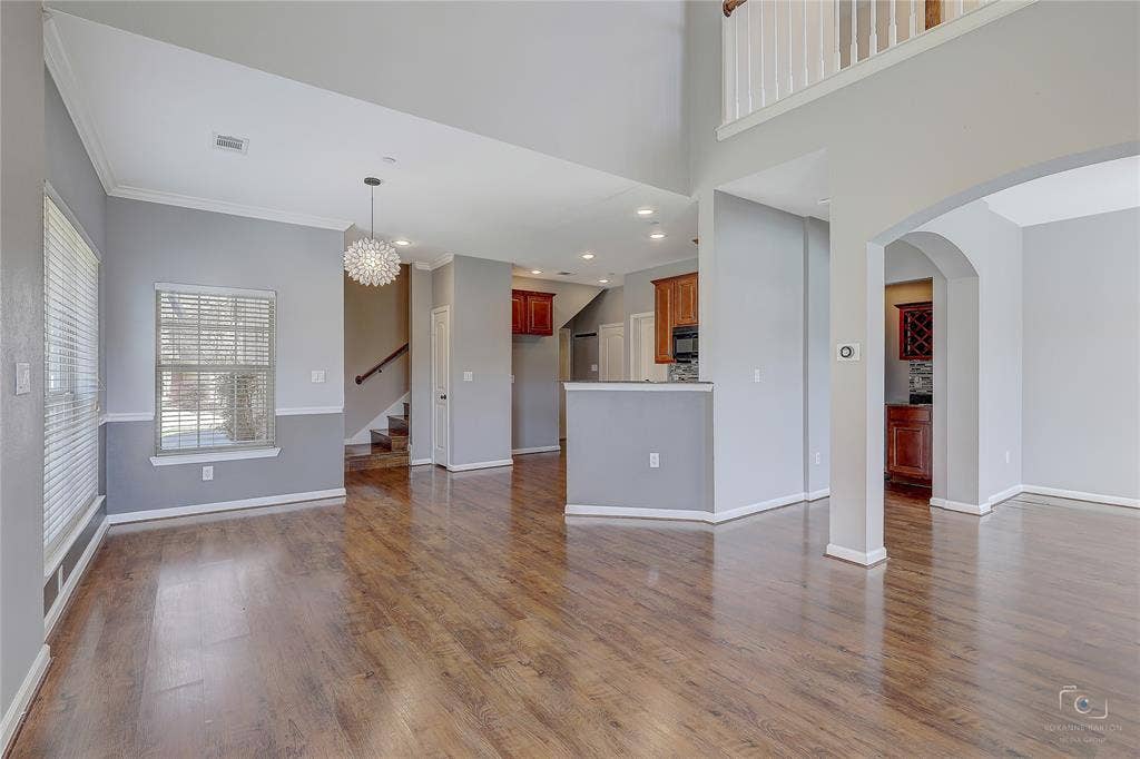 Open-concept interior featuring wood-finish flooring, two-story vaulted ceiling, arched architectural openings, recessed lighting, and a pendant fixture