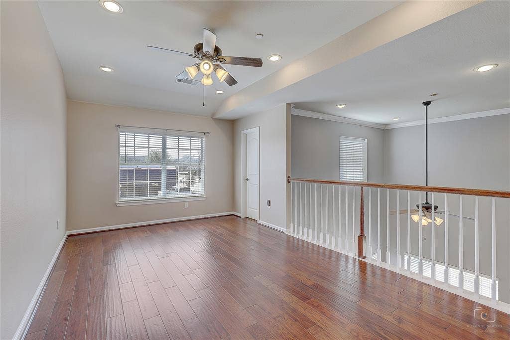 Open space featuring wood-finish flooring, recessed lighting, a ceiling fan with integrated light kit, and a white balustrade with a wood-finish handrail