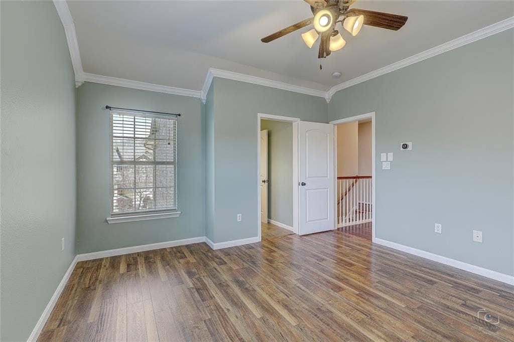 Room featuring wood-finish flooring, crown molding, a multi-light ceiling fan, and a single-hung window with a grid pattern