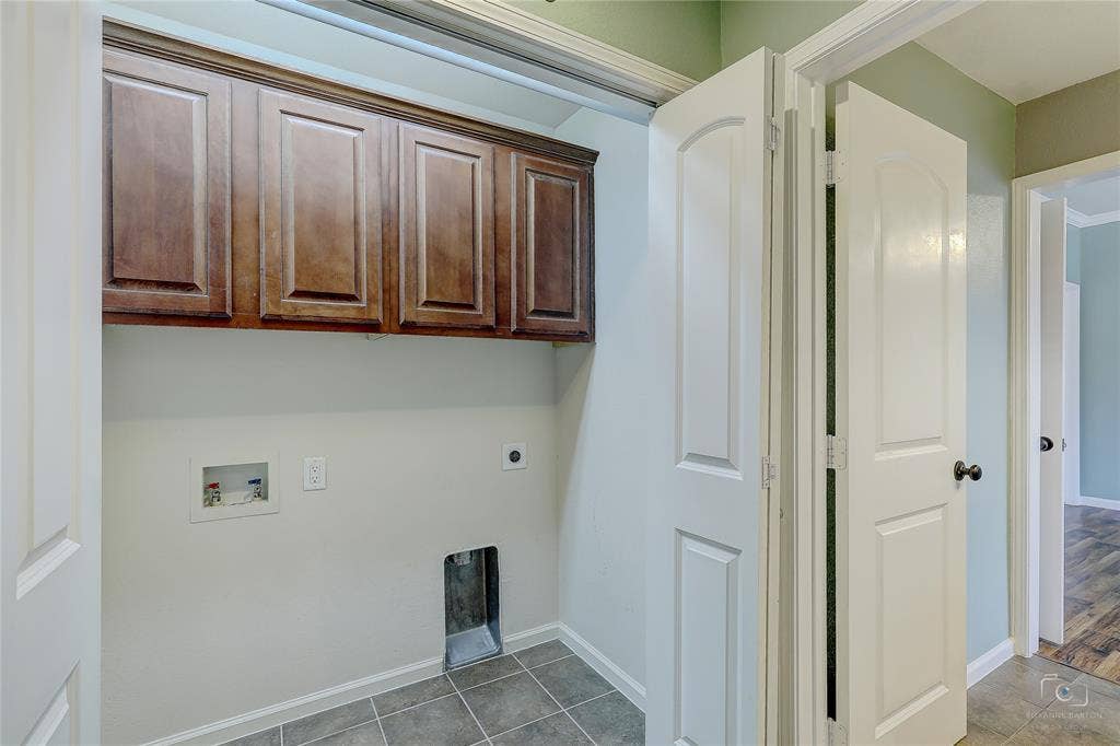 Dedicated utility space featuring stained wood cabinetry, tile flooring, and arched-panel interior doors