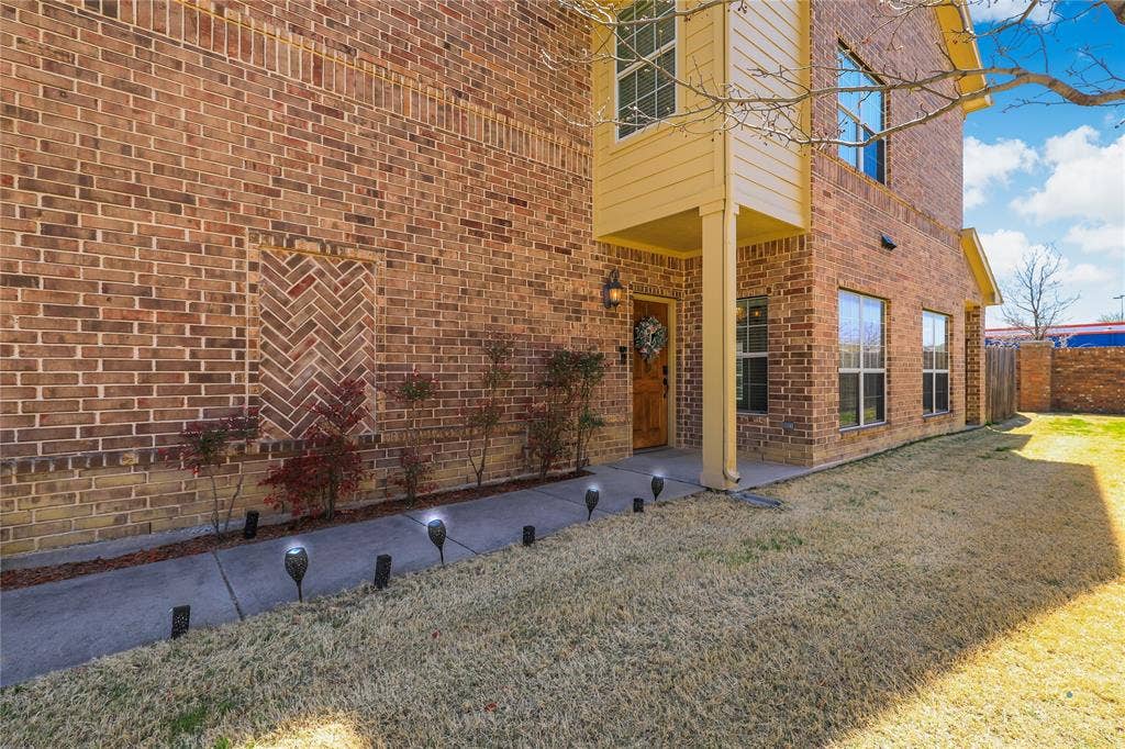 Multi-story brick exterior featuring herringbone masonry detailing, a concrete walkway, and a covered entryway