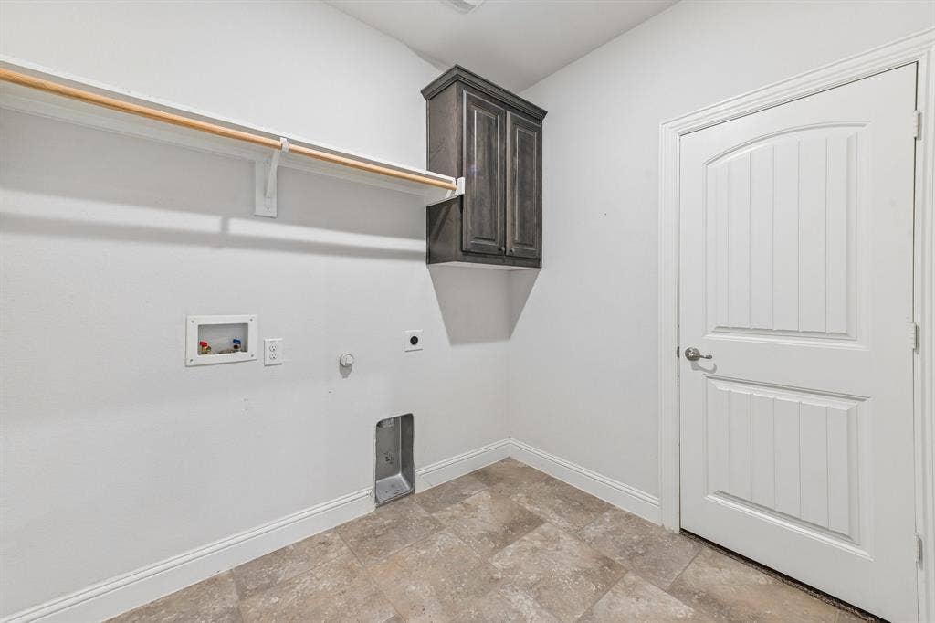 284 Goliad Trail, Forney, TX 75126 Utility space featuring tile flooring, wall-mounted dark wood-finish cabinetry, a built-in hanging rod, and a multi-panel door