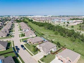 284 Goliad Trail, Forney, TX 75126 Aerial perspective of residential properties featuring brick-facade homes, multi-pitched shingle roofing, concrete driveways, and expansive greenbelt areas