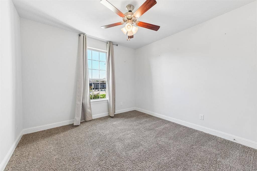 284 Goliad Trail, Forney, TX 75126 Neutral wall tones, wall-to-wall carpeting, window with grid panes, and ceiling fan with integrated light fixture