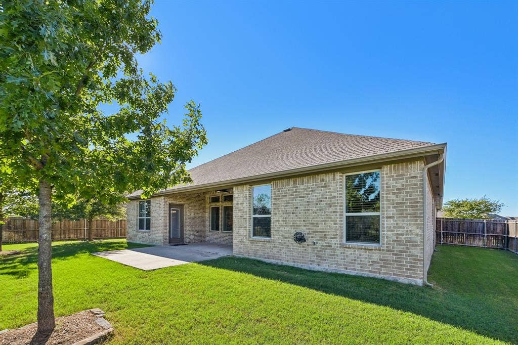 284 Goliad Trail, Forney, TX 75126 Brick exterior, rear concrete patio, and fenced yard with mature trees