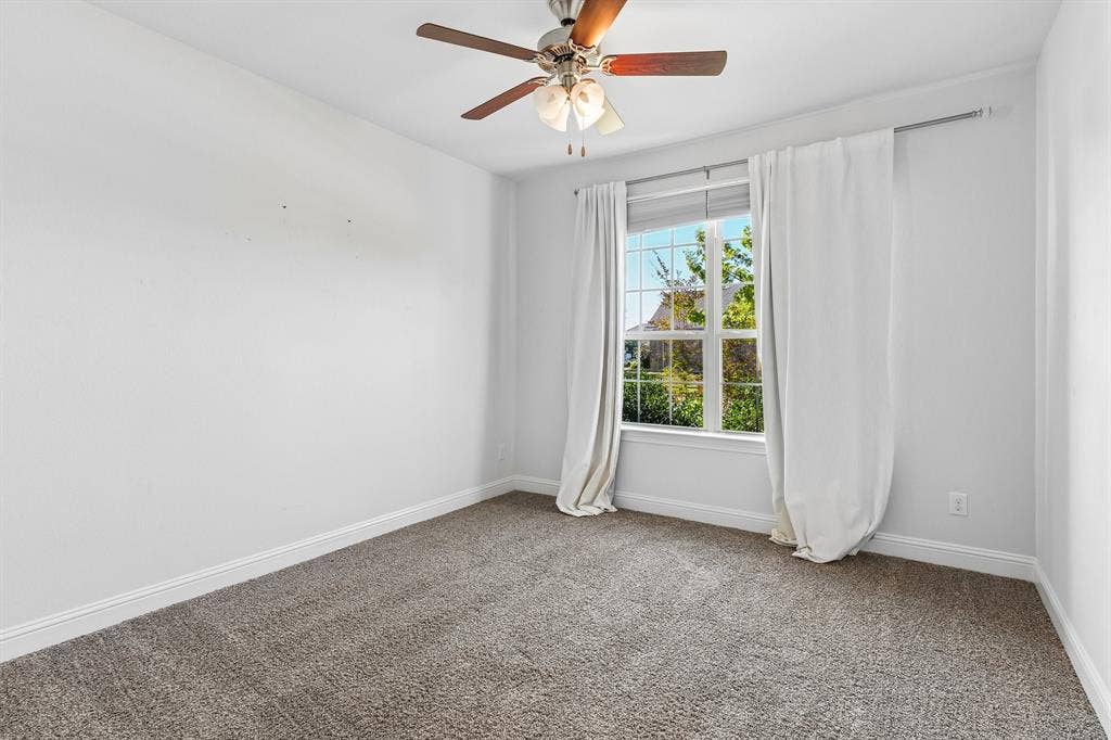 284 Goliad Trail, Forney, TX 75126 Neutral-toned carpeting, multi-pane window with natural light, and ceiling-mounted light fixture with wooden fan blades