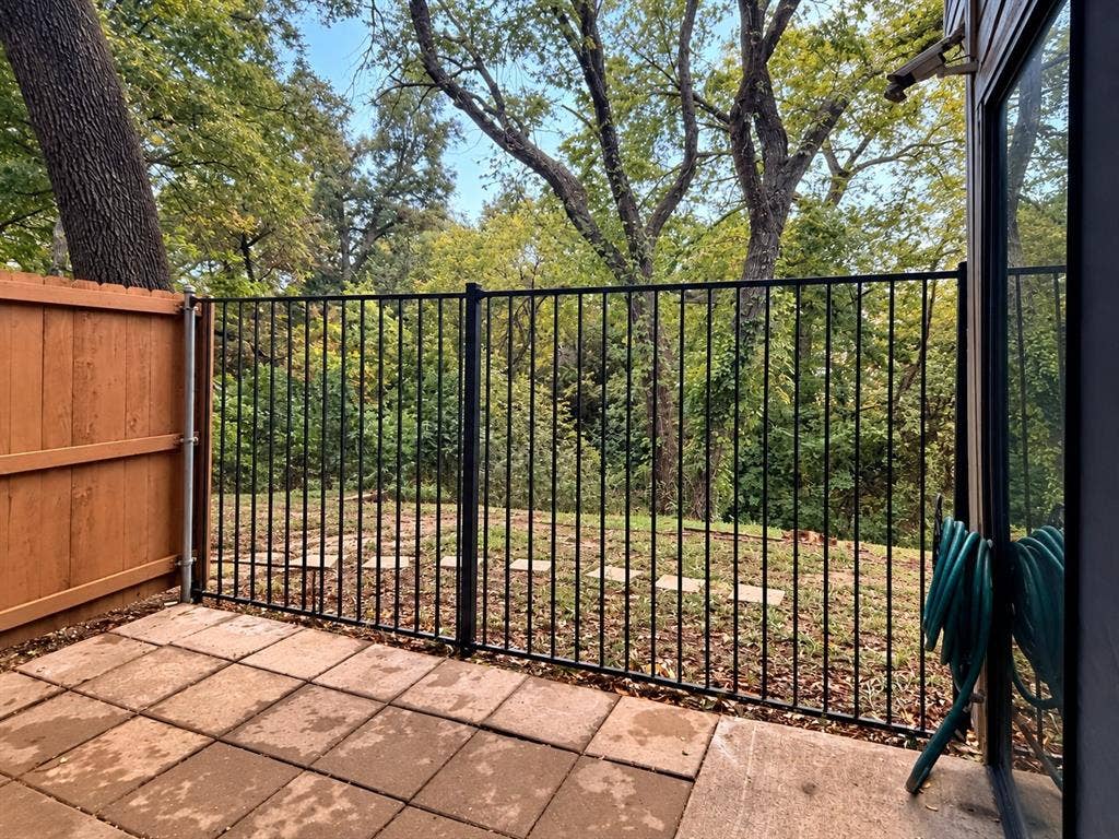 895 Dublin Drive, #4, Richardson, TX 75080 Concrete paver patio featuring black metal perimeter fencing, wood privacy screen, and stone stepping stones