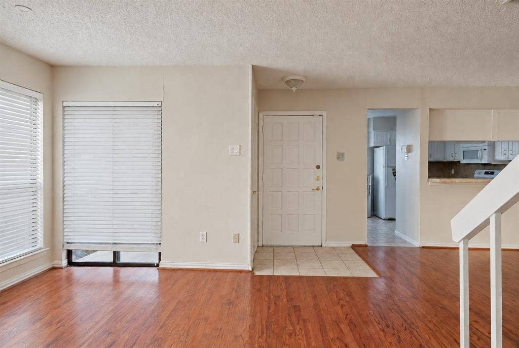 895 Dublin Drive, #4, Richardson, TX 75080 Wood-finish flooring, tiled entryway, white paneled front door, and white staircase railing