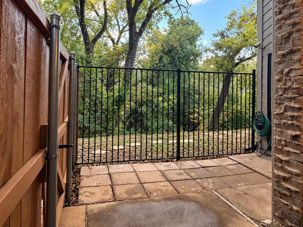 895 Dublin Drive, #4, Richardson, TX 75080 Concrete paver patio featuring a black metal perimeter fence, solid wood privacy fencing, and masonry exterior wall