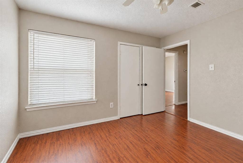 895 Dublin Drive, #4, Richardson, TX 75080 Room featuring wood-finish flooring, a neutral wall palette, a dual-panel closet door, and a horizontal slatted window blind