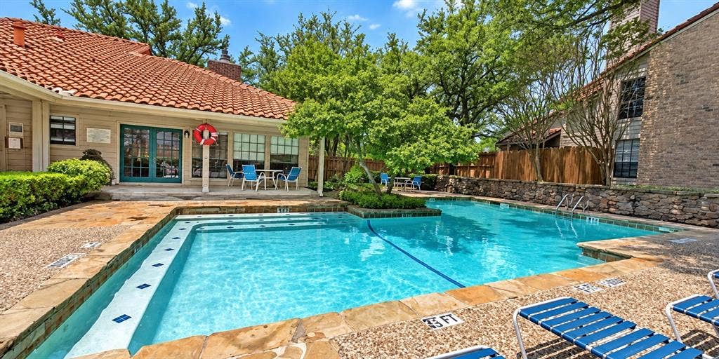 895 Dublin Drive, #4, Richardson, TX 75080 In-ground swimming pool featuring a stone-tile surround, built-in entry steps, and a decorative stone perimeter wall
