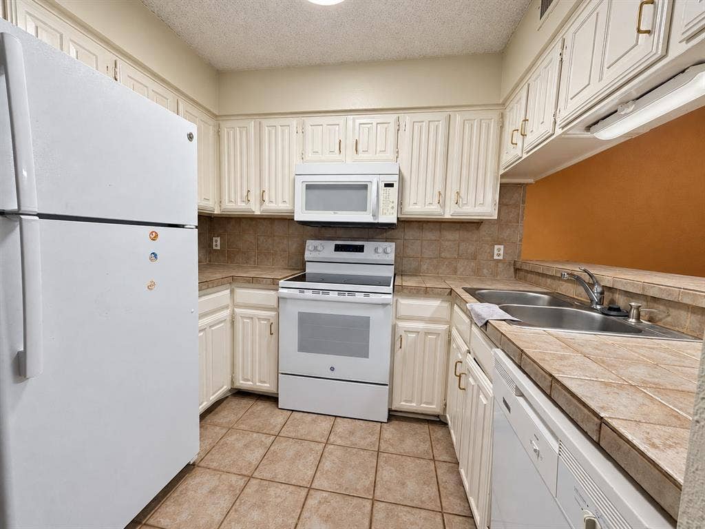 895 Dublin Drive, #4, Richardson, TX 75080 Kitchen featuring white cabinetry, tile countertops and backsplash, tile flooring, and white built-in appliances including a refrigerator, electric range, microwave, and dishwasher