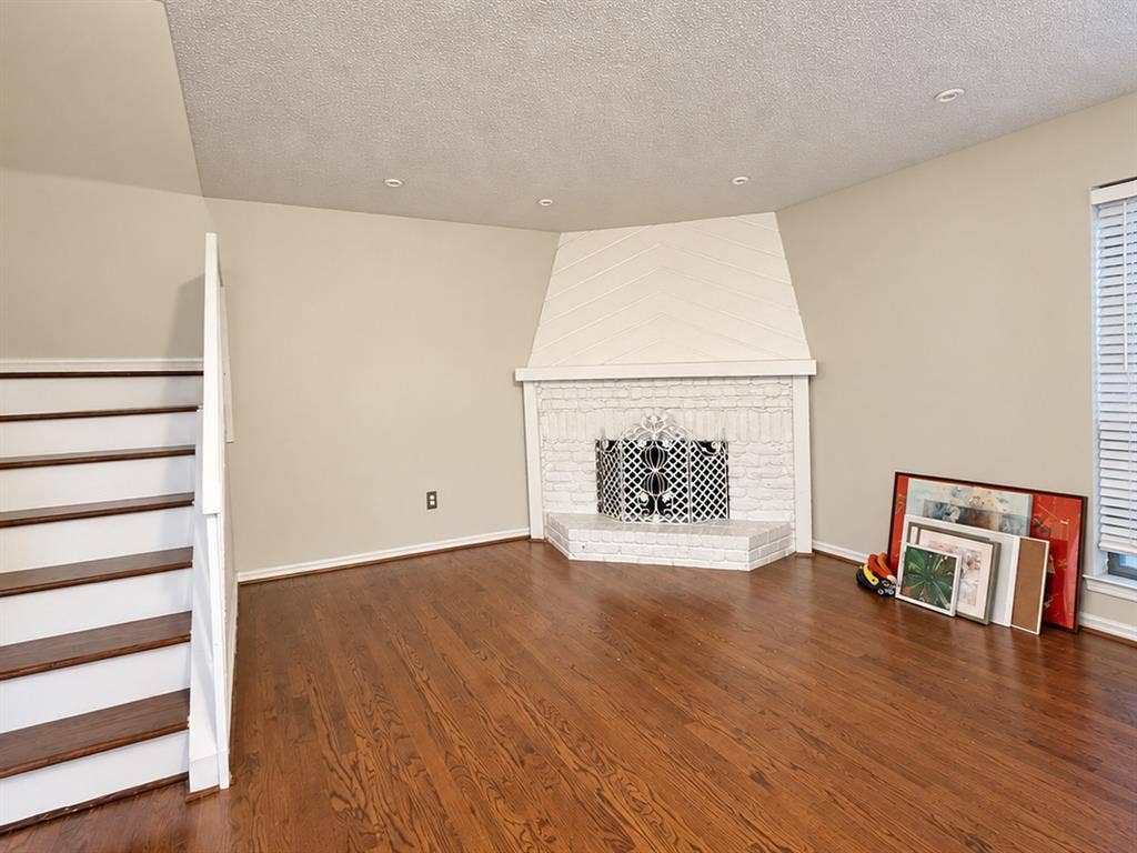 895 Dublin Drive, #4, Richardson, TX 75080 Corner fireplace with white painted brick surround and integrated geometric paneling, wood-finish flooring, and recessed ceiling lighting