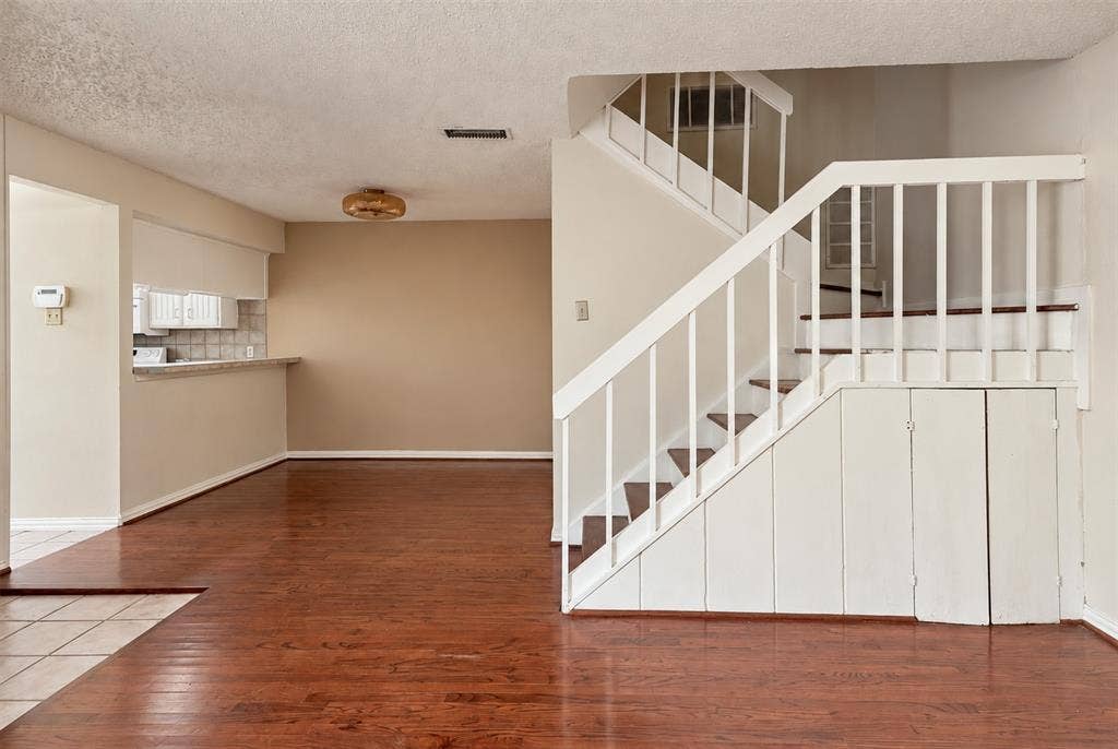 895 Dublin Drive, #4, Richardson, TX 75080 Wood-finish flooring throughout common area, white staircase with vertical balusters, and integrated under-stair storage cabinetry