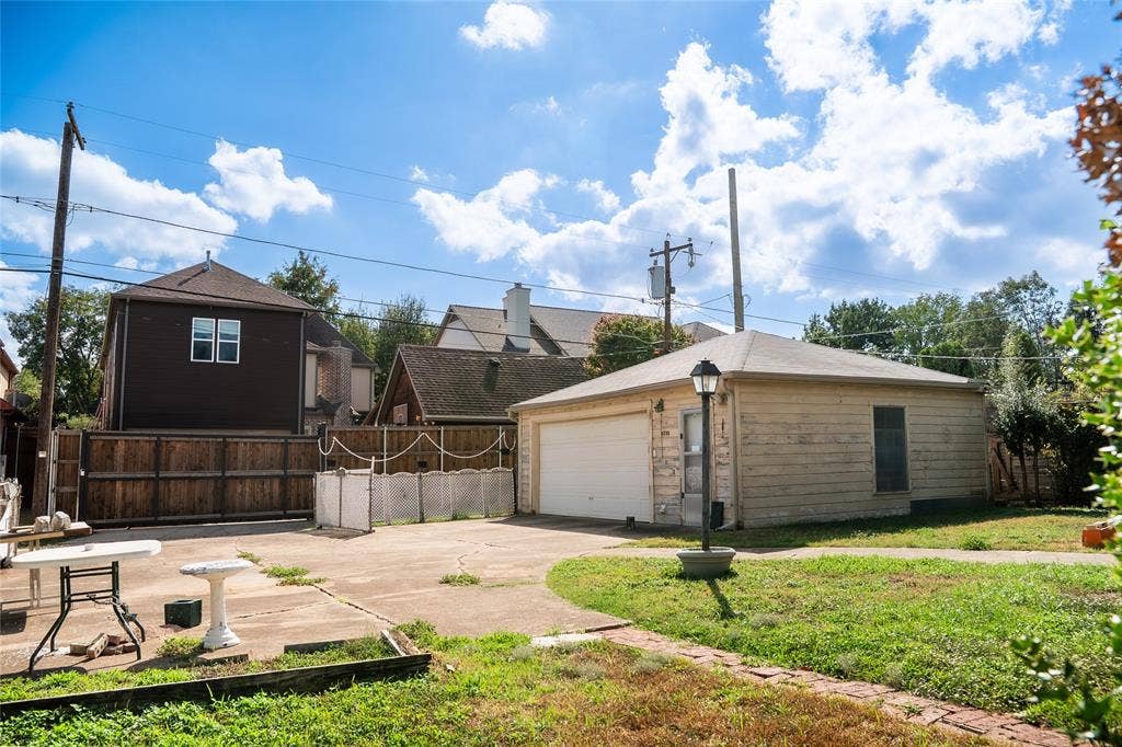 Detached garage with horizontal siding, concrete parking area, and perimeter wood fencing